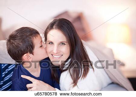 Stock Photo - Son kissing mothers cheek under duvet. Fotosearch