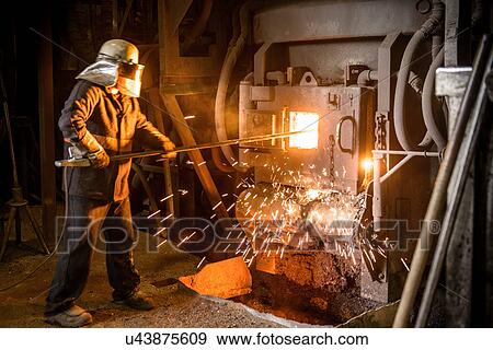 Stock Photo - Steel worker in front of furnace in steel foundry. Fotosearch