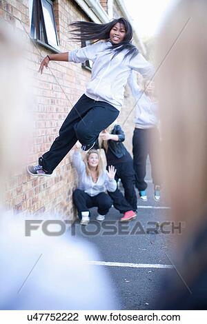 Stock Image - Teenage girl dancing against brick wall. Fotosearch