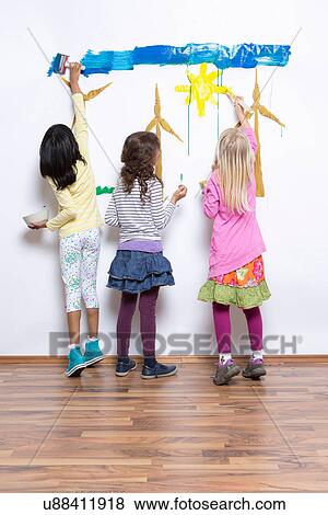 Three girls painting wind turbines on wall View Large Photo Image Stock Photo - Three girls painting wind turbines on wall. Fotosearch