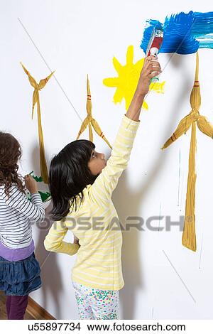 Two girls painting wind turbines on wall View Large Photo Image Picture - Two girls painting wind turbines on wall. Fotosearch