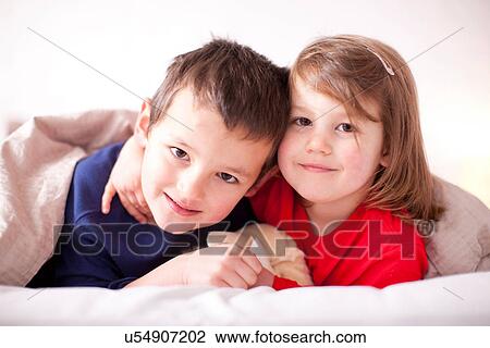 Two young children hugging under duvet View Large Photo Image Stock Image - Two young children hugging under duvet. Fotosearch