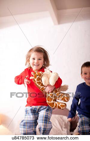 Two young children jumping on bed View Large Photo Image Stock Image - Two young children jumping on bed. Fotosearch