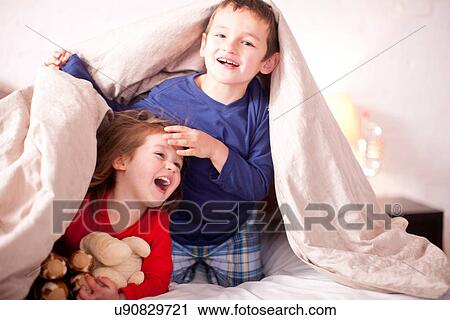 Stock Image - Two young children playing under duvet. Fotosearch