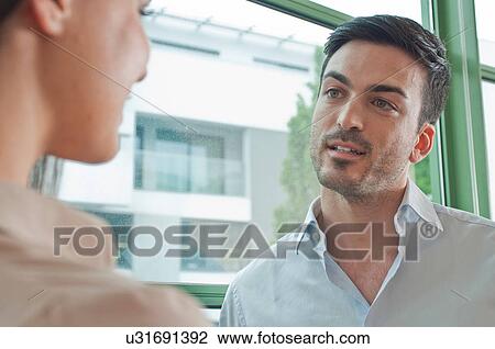 Two young colleagues having flirtatious meeting in office View Large Photo Image Stock Image - Two young colleagues having flirtatious meeting in office. Fotosearch