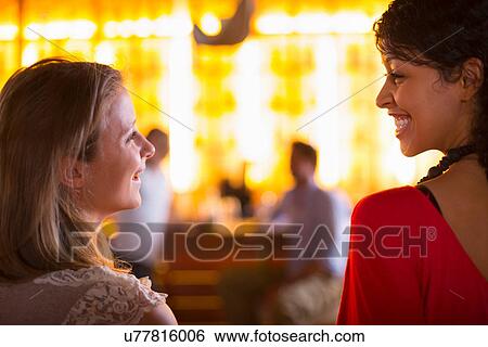 Two young females talking in bar View Large Photo Image Stock Photograph - Two young females talking in bar. Fotosearch