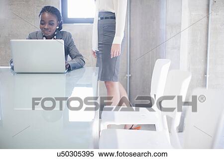Stock Photography - Two young women in boardroom. Fotosearch