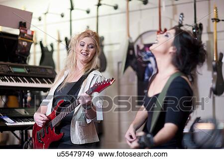 Two young women trying electric guitars in music store View Large Photo Image Stock Photo - Two young women trying electric guitars in music store. Fotosearch