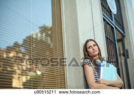 Unhappy young woman holding files outside city office View Large Photo Image Stock Image - Unhappy young woman holding files outside city office. Fotosearch