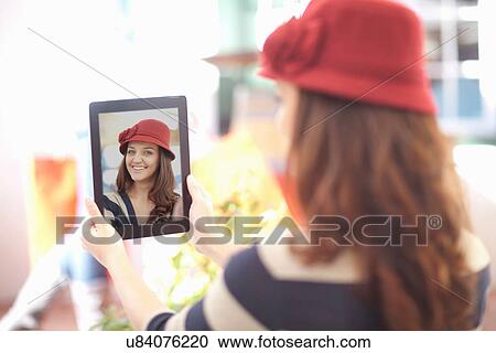 Woman in burgundy hat taking self portrait on digital tablet View Large Photo Image Stock Image - Woman in burgundy hat taking self portrait on digital tablet. Fotosearch
