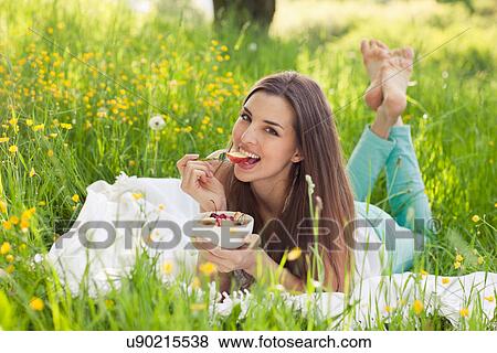 Stock Photo - Woman in field of buttercups eating fresh fruit. Fotosearch