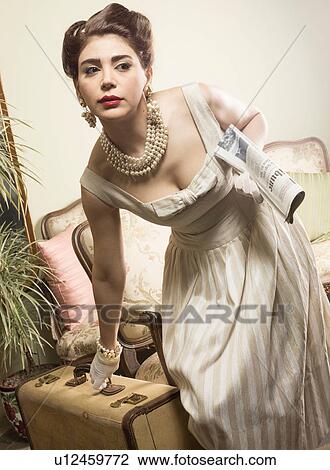 Woman in vintage clothes picking up suitcase View Large Photo Image Stock Image - Woman in vintage clothes picking up suitcase. Fotosearch