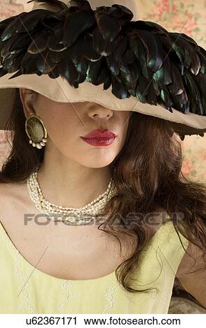 Stock Image - Woman in wide brimmed hat with feathers. Fotosearch