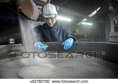 Worker checking container of steel shot in steel foundry View Large Photo Image Stock Image - Worker checking container of steel shot in steel foundry. Fotosearch