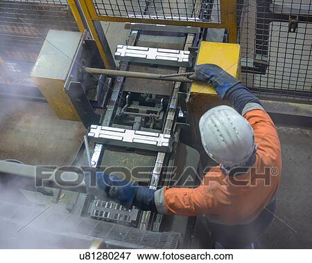 Stock Photo - Worker moving metal ingots at aluminum recycling plant. Fotosearch