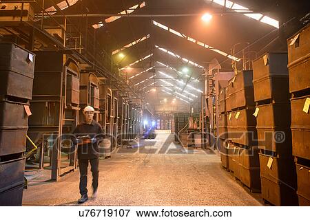 Worker walking past crates of steel shot in steel foundry View Large Photo Image Stock Photo - Worker walking past crates of steel shot in steel foundry. Fotosearch