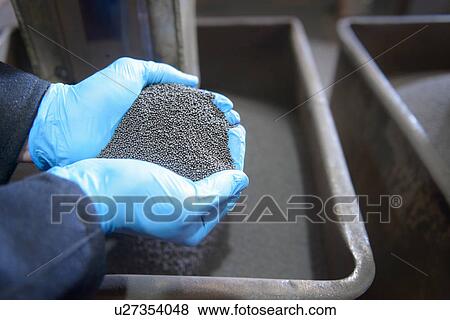 Stock Photo - Worker with handful of steel shot in steel foundry. Fotosearch