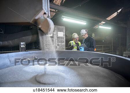 Picture - Workers monitoring container of steel shot in steel foundry. Fotosearch