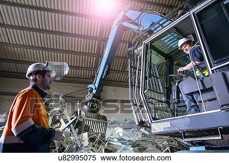 Stock Photography - Workers talking in aluminum recycling plant. Fotosearch