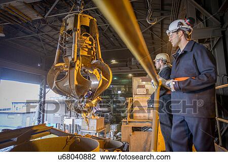 Workers watching mechanical grabber in steel foundry View Large Photo Image Stock Image - Workers watching mechanical grabber in steel foundry. Fotosearch