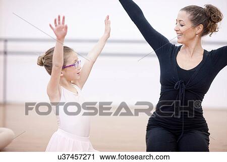 Stock Image - Young ballerina copying teachers pose. Fotosearch