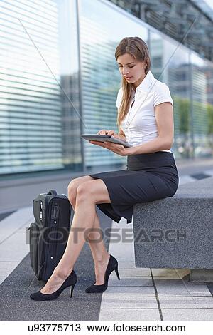 Stock Image - Young businesswoman sitting and using digital tablet. Fotosearch