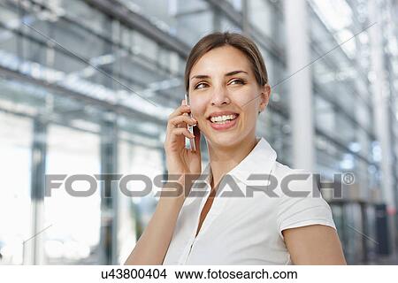 Young businesswoman using mobile phone, smiling View Large Photo Image Picture - Young businesswoman using mobile phone, smiling. Fotosearch