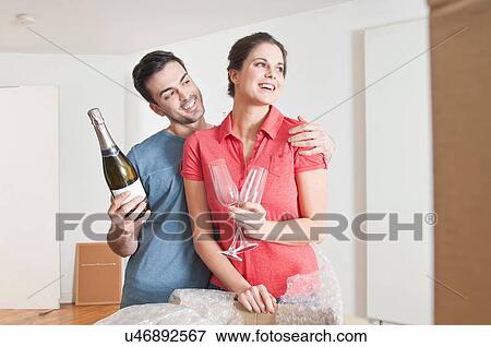 Stock Photo - Young couple celebrating house move with champagne. Fotosearch