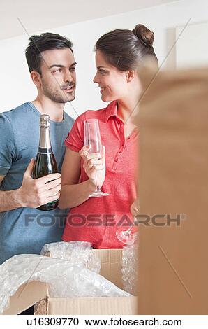 Young couple celebrating with champagne amongst cardboard boxes View Large Photo Image Stock Image - Young couple celebrating with champagne amongst cardboard boxes. Fotosearch