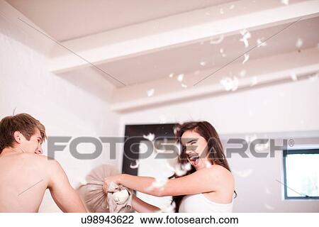 Stock Image - Young couple having a pillow fight. Fotosearch