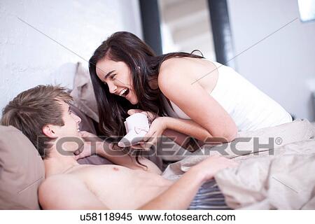 Young couple in bed looking at baby booties View Large Photo Image Stock Photography - Young couple in bed looking at baby booties. Fotosearch