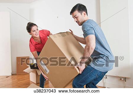Stock Image - Young couple lifting cardboard box. Fotosearch