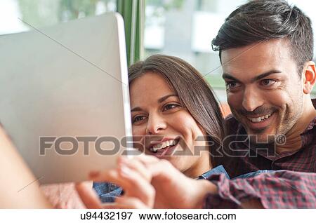 Young couple looking at digital tablet View Large Photo Image Stock Photo - Young couple looking at digital tablet. Fotosearch