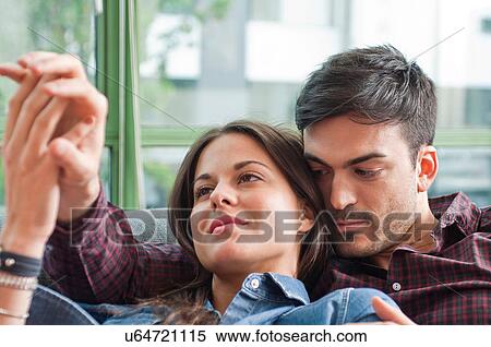 Young couple lounging on sofa holding hands View Large Photo Image Stock Photography - Young couple lounging on sofa holding hands. Fotosearch