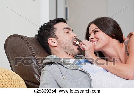 Young couple lying on sofa sharing popcorn View Large Photo Image Picture - Young couple lying on sofa sharing popcorn. Fotosearch