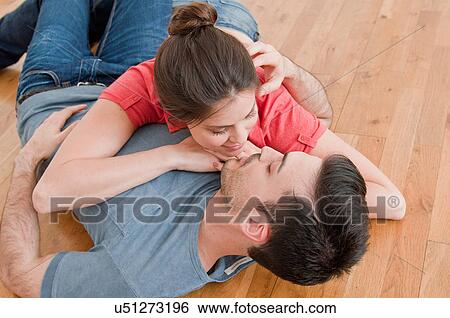 Stock Photograph - Young couple lying together on wooden floor. Fotosearch