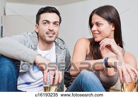 Stock Photography - Young couple sitting down sharing glass of wine. Fotosearch