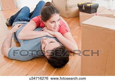 Stock Photograph - Young couple taking a break amongst cardboard boxes. Fotosearch