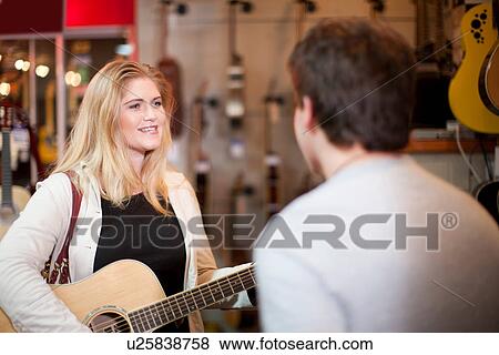 Young couple trying guitar in music store View Large Photo Image Stock Photo - Young couple trying guitar in music store. Fotosearch