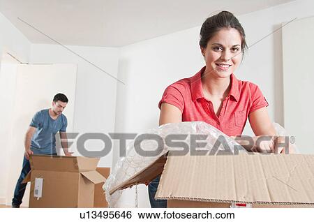 Stock Photograph - Young couple unpacking cardboard boxes. Fotosearch