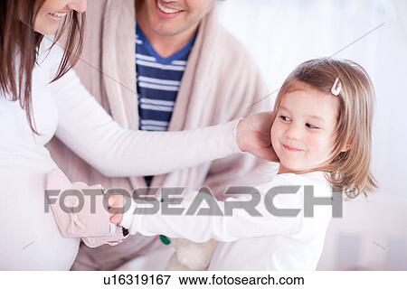 Stock Photo - Young daughter holding baby booties on mothers bump. Fotosearch