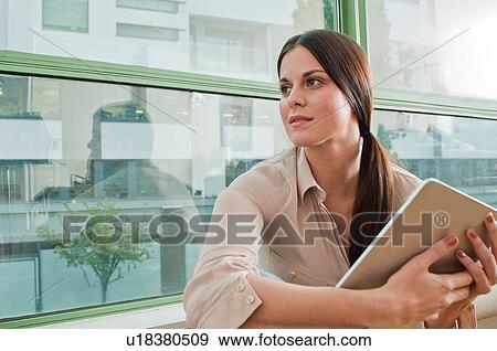 Young female holding at digital tablet in office View Large Photo Image Stock Photo - Young female holding at digital tablet in office. Fotosearch