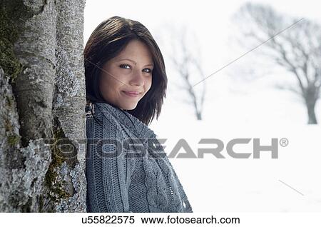 Young female leaning against bare tree in snowy field View Large Photo Image Stock Photography - Young female leaning against bare tree in snowy field. Fotosearch
