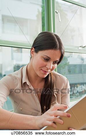 Young female looking at digital tablet in office View Large Photo Image Stock Photography - Young female looking at digital tablet in office. Fotosearch