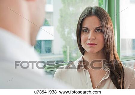 Stock Photo - Young female office worker face to face with male colleague. Fotosearch