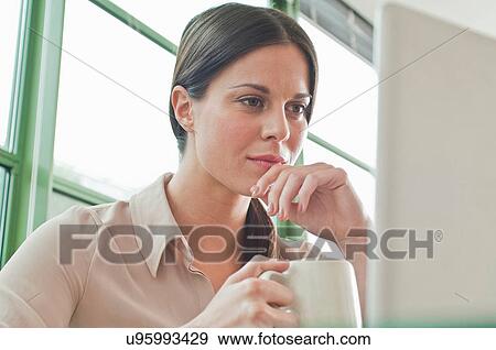 Young female office worker looking at laptop View Large Photo Image Stock Photo - Young female office worker looking at laptop. Fotosearch
