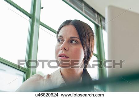 Young female office worker looking out of window View Large Photo Image Picture - Young female office worker looking out of window. Fotosearch