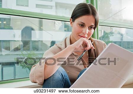 Stock Photo - Young female reading documentation in office. Fotosearch