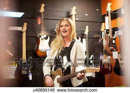 Young female testing guitar in music store View Large Photo Image Stock Photo - Young female testing guitar in music store. Fotosearch