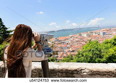 Stock Image - Young female tourist looking through coin operated binoculars in Lisbon, Portugal. Fotosearch